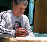 Local artist sketching on copal wood to create alebrijes