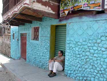 Patrick sitting and waiting by a colorful turquoise building on location