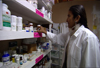 Dr. Mendoza looking at the shelf of medications in the pharmacy